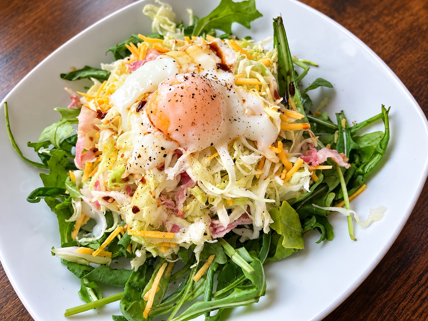 Weißkohlsalat mit Bacon, Rucola, geriebenem Käse und einem Onsen-Ei.