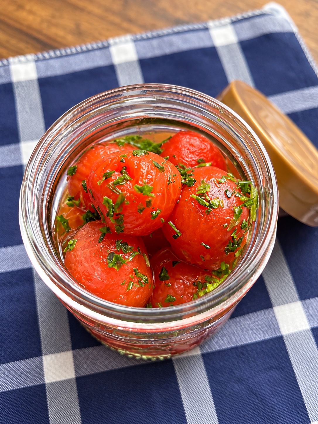 Peeled cherry tomatoes with parsley in a glass jar