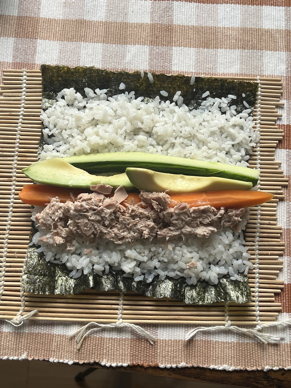 Thunfisch, Avocado, Gurke und Karotte liegen zum Rollen auf Sushi-Reis