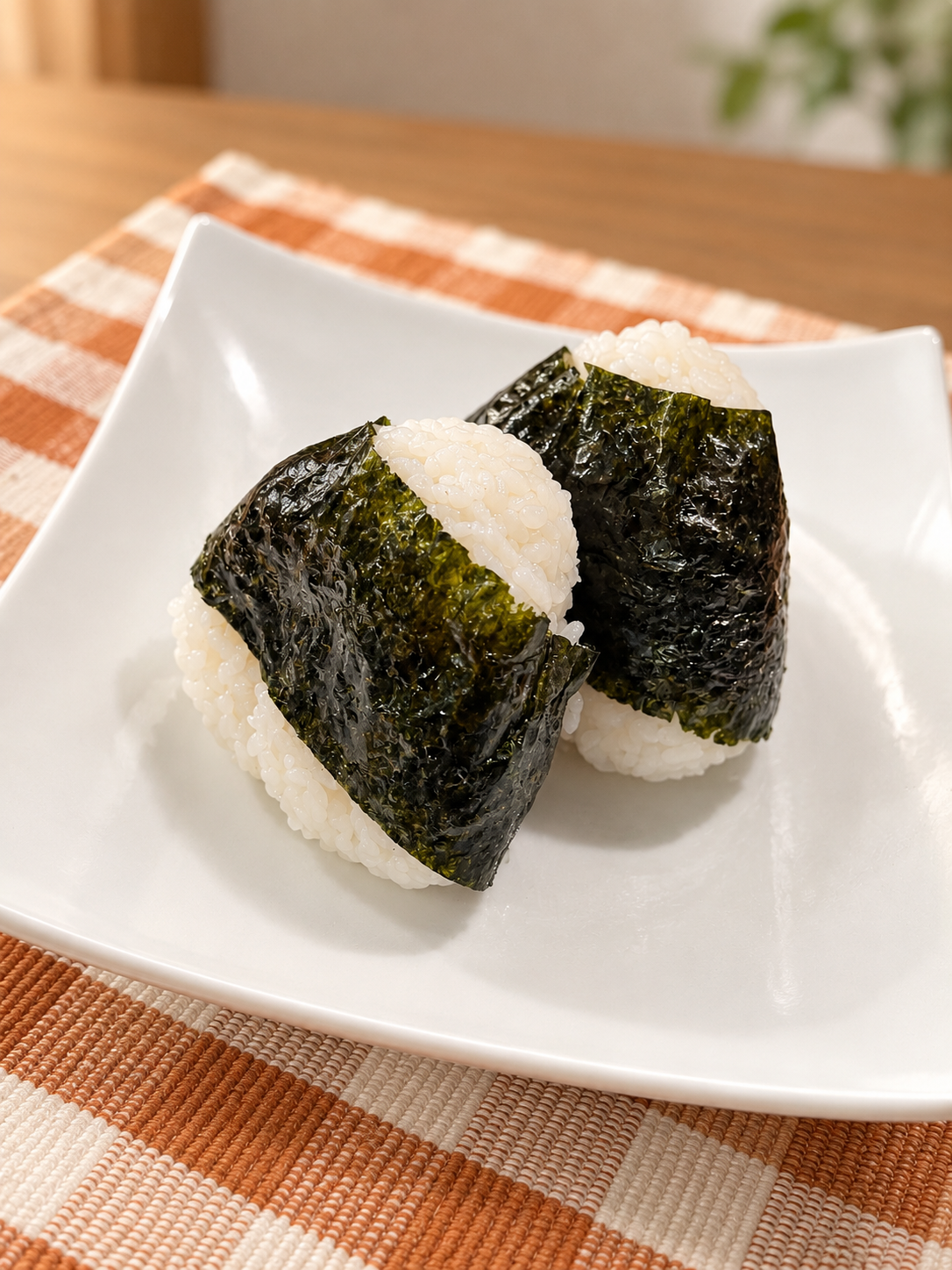 Zwei Onigiri mit Nori auf einem weißen Teller