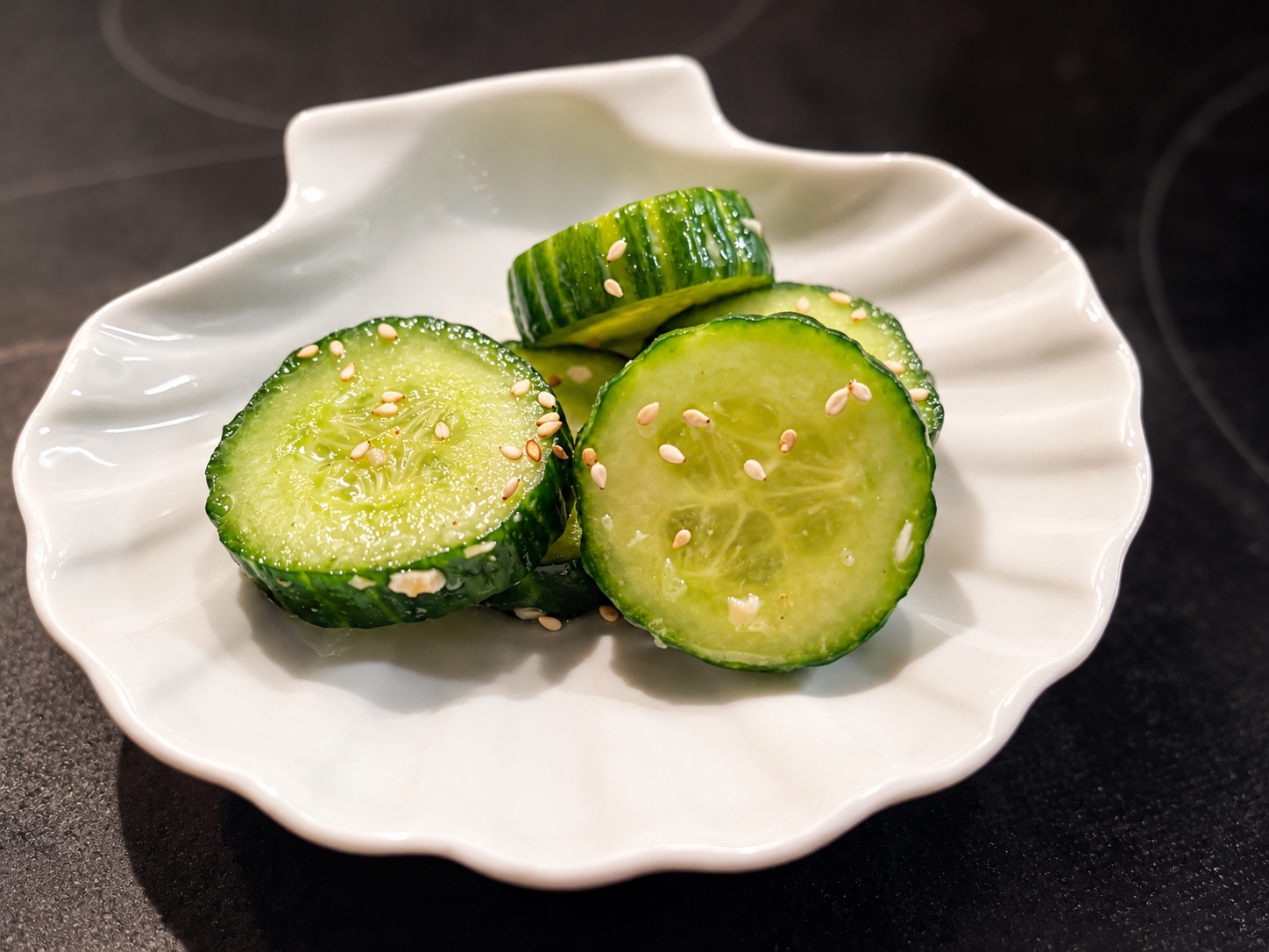 Dicke Wasabi-Gurkenscheiben mit weißem Sesam auf einem weißen Teller
