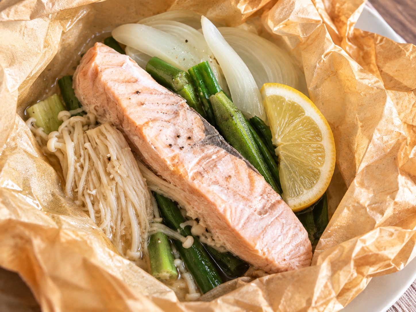 Gedämpfter Lachs mit Pilzen und Gemüse im geöffneten Backpapier