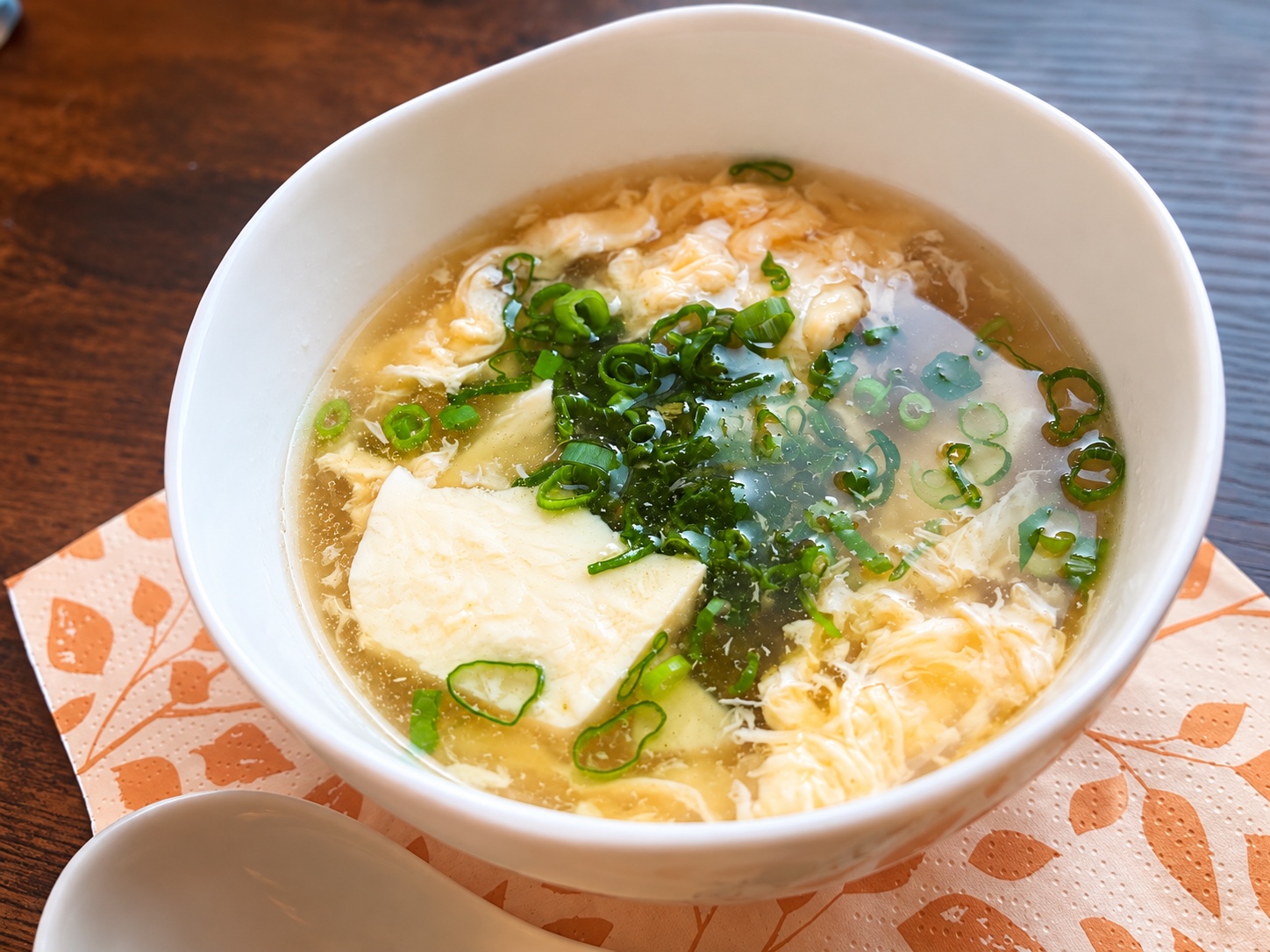Seidentofu und lockeres Ei in einer klaren Suppe mit Frühlingszwiebeln