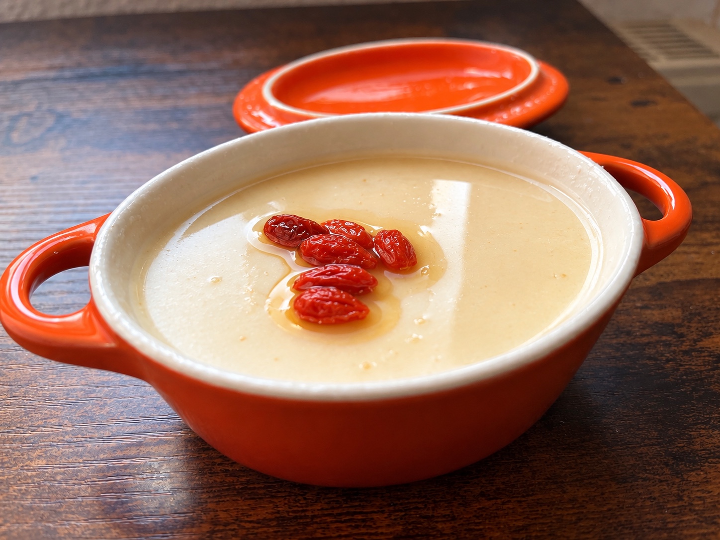 Sesampudding mit Honig und Gojibeeren in einer orangefarbenen Keramikschale