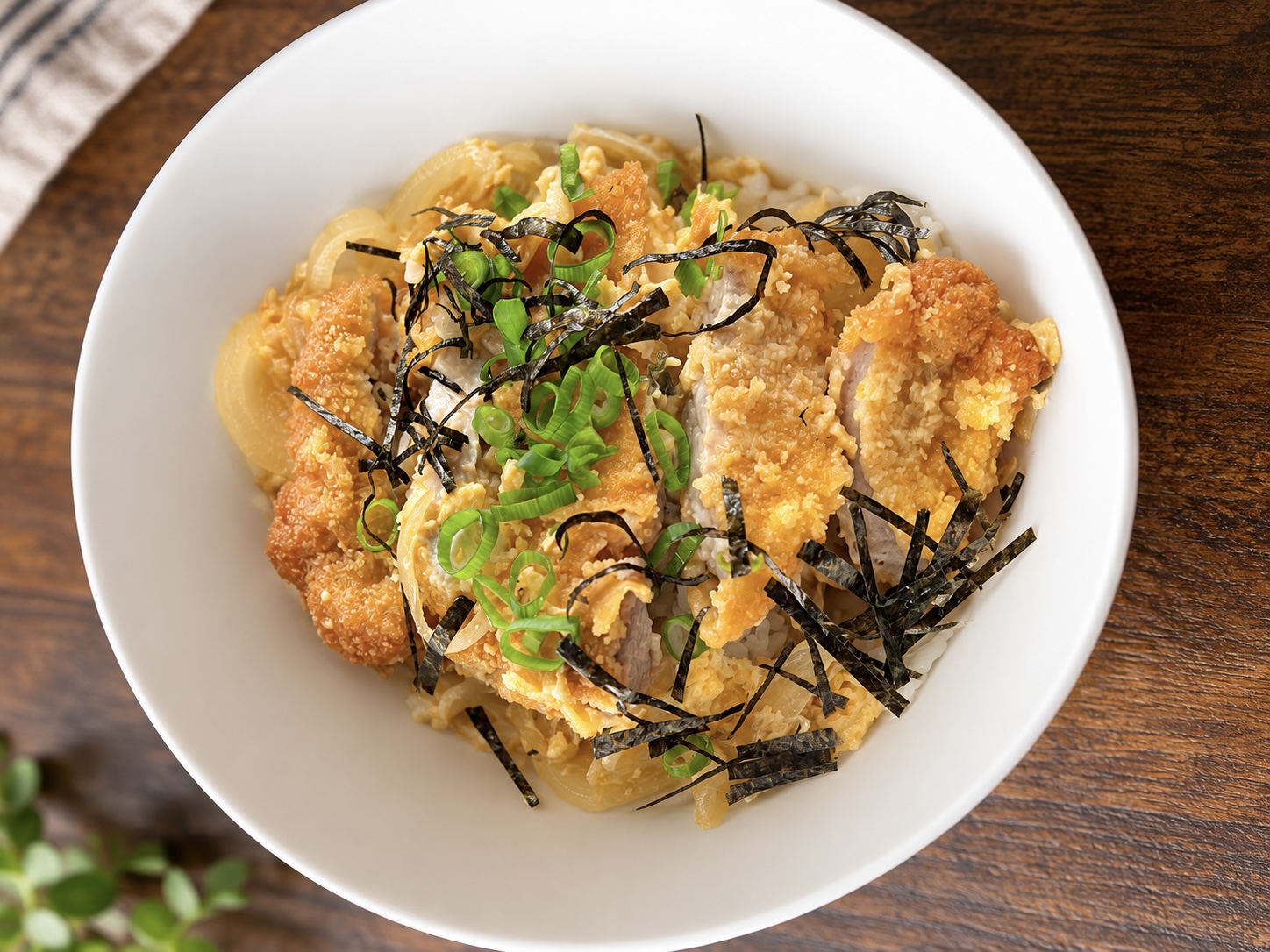 Katsudon with crispy schnitzel, egg, onion, green onion and nori over rice